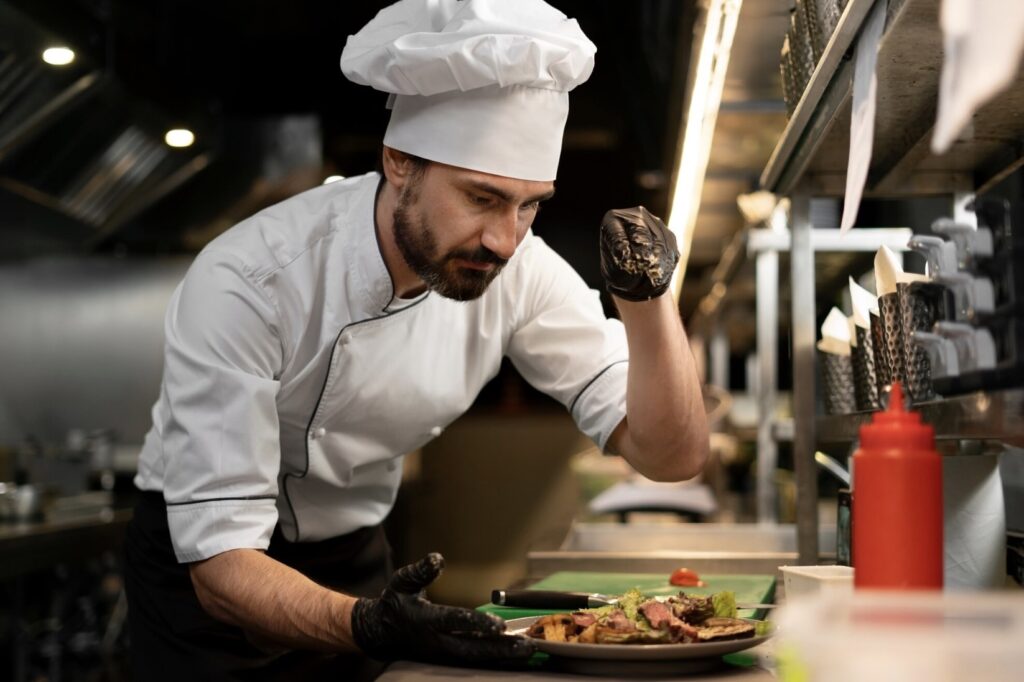 Szef kuchni w restauracji posypuje sałatkę przyprawami na kuchni.
