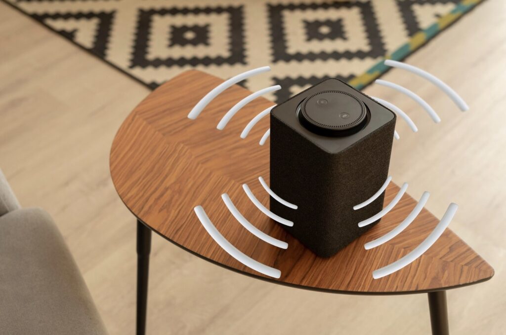 Stereo speaker on a small table with sound waves radiating outward in all directions.