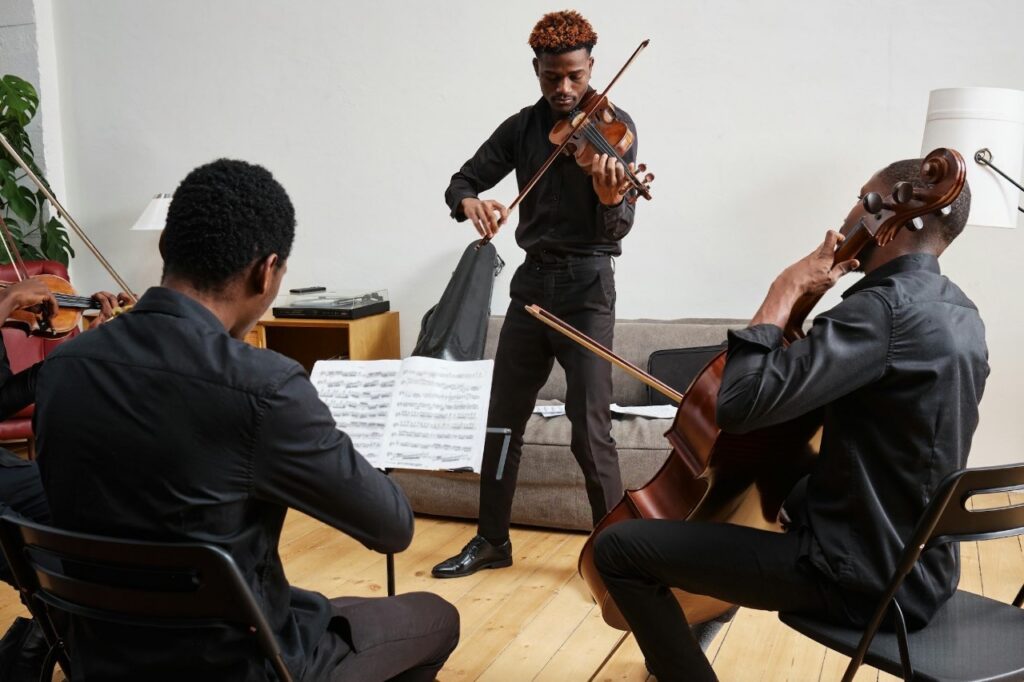 A string quartet of Black musicians playing classical instruments like violin and cello to reduce stress and lower cortisol levels.