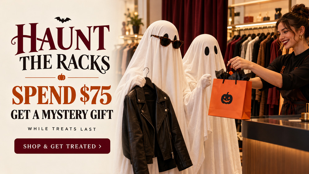 Two people dressed as ghosts, one wearing sunglasses and holding a black leather jacket, receive an orange shopping bag from a smiling sales associate in a clothing boutique next to a "HAUNT THE RACKS" promotional text overlay.